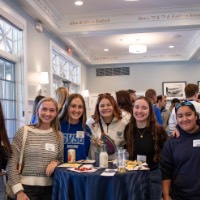 Alumnae stand and posed together inside the Alumni House